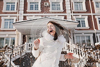 Portrait excited playful girl having fun with snow in frozen sunny morning on street. True emotions, laughing with Stock Photo