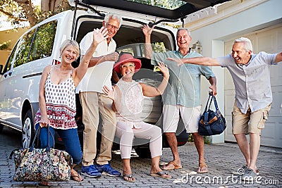 Portrait Of Excited Senior Friends Loading Luggage Into Trunk Of Car About To Leave For Vacation Stock Photo