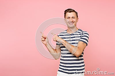 Portrait excited smiling young man wearing striped t-shirt pointing index fingers aside on copy space isolated on Stock Photo