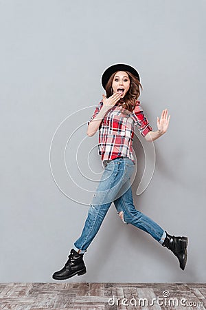 Portrait of an excited young woman in plaid shirt jumping Stock Photo