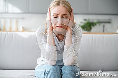 Portrait of exhausted woman suffering from disturbing noisy sound at home Stock Photo