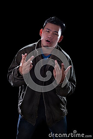 portrait face of young asian man acting like a rocker man standing against dark background Stock Photo