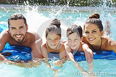 Portrait Of Family On Airbed In Swimming Pool Stock Photo