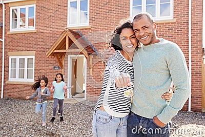 Portrait Of Family Holding Keys Standing Outside New Home On Moving Day Stock Photo