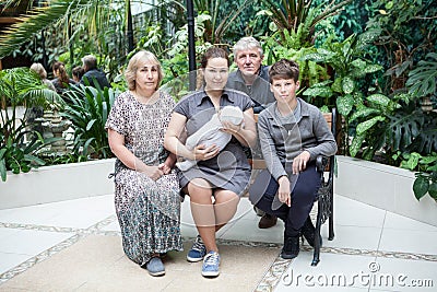 Portrait of family from mother with newborn baby and preteen son, grandparents. Sitting together on bench Stock Photo