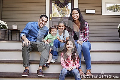 Portrait Of Family Sitting On Steps in Front Of House Stock Photo