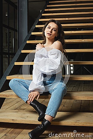 Portrait fashion woman sit on the stairs inside stylish designe interior room Stock Photo