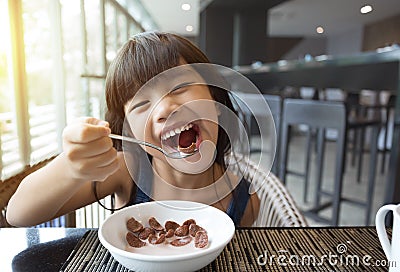 Portrait of feeling happy a young girl having breakfast on table Stock Photo