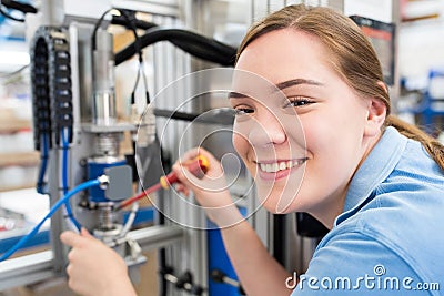 Portrait Of Female Apprentice Engineer Working On Machine In Factory Stock Photo