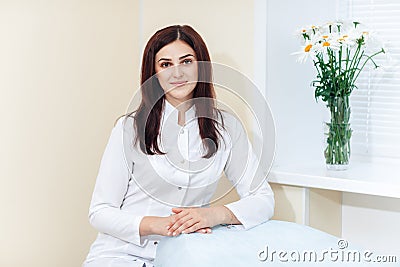 Female brunette cosmetologist in uniform near the window in the cosmetology office Stock Photo