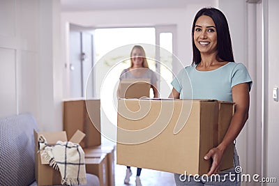 Portrait Of Female Couple Carrying Boxes Through Front Door Of New Home On Moving Day Stock Photo