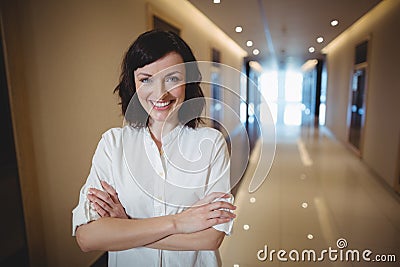 Portrait of female executive standing with arms crossed in corridor Stock Photo