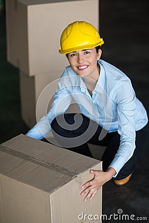 Portrait of female factory worker picking up cardboard boxes Stock Photo