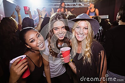 Portrait of female friends with disposable cups in club Stock Photo