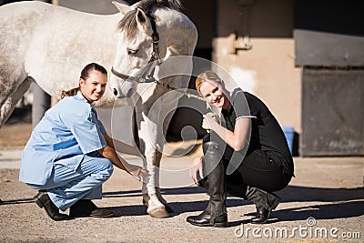 Portrait of female jockey and vet crouching by horse Editorial Stock Photo