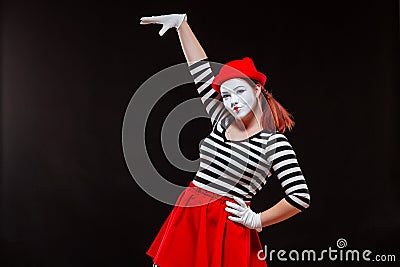 Portrait of female mime artist performing, isolated on black background. Woman raised her hand up. A symbol of growth Stock Photo