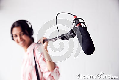 Portrait Of Female Sound Recordist Holding Microphone On Video Film Production In White Studio Stock Photo