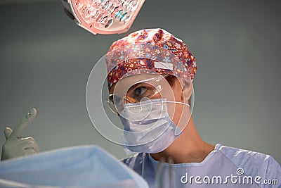 Portrait of a female surgeon in a modern operating room, a professional surgeon in a mask with glasses and gloves. Stock Photo