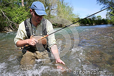 Portrait of fisherman in river catching brown trout Stock Photo