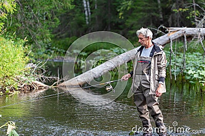 Portrait of fisherman in waders with spinning rod on river. Spinning fishing Stock Photo