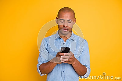 Portrait of focused handsome youth hod hand modern technology search information isolated over yellow background Stock Photo