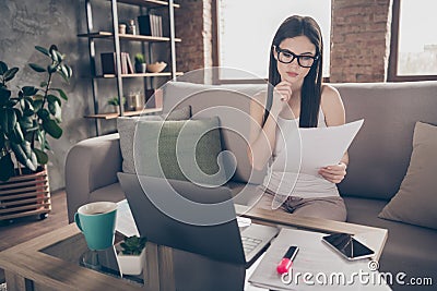 Portrait of focused minded girl representative sit divan work remote hold paper read progress development statistics Stock Photo