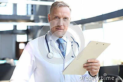 Portrait of focused senior doctor writing reports Stock Photo