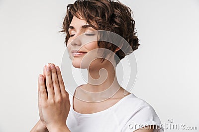 Portrait of focused woman with short brown hair in basic t-shirt keeping palms together and praying Stock Photo