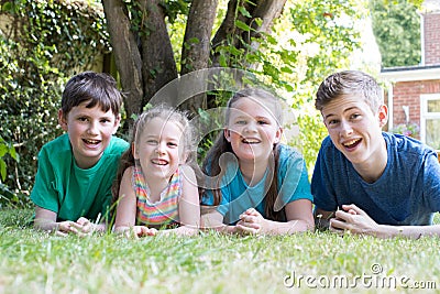 Portrait Of Four Brothers And Sisters Lying In Garden At Home Stock Photo