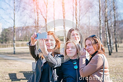 Portrait of four trendy girlfriends with hairstyles wearing stylish sunglasses making faces and smiling while taking Stock Photo