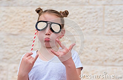 Funny little girl with paper glasses carnival mask having fun on white wall background. Stock Photo