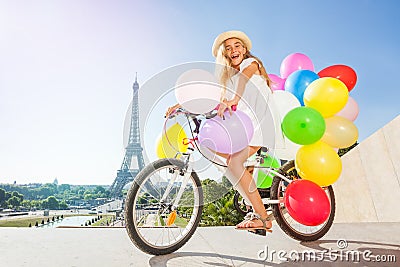 Happy French girl cycling with colorful balloons Stock Photo