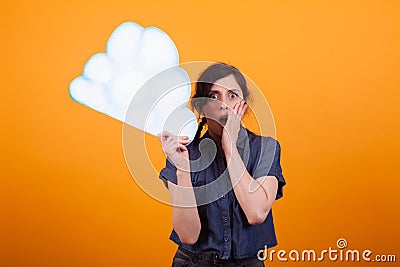 Portrait of friendly shocked woman with thought clound in her hand over yellow background in studio Stock Photo