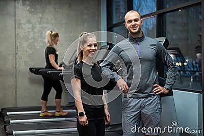 Portrait of friends standing with woman exercising on treadmill Stock Photo