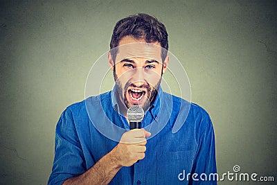 Portrait frustrated man with microphone isolated on gray wall background Stock Photo