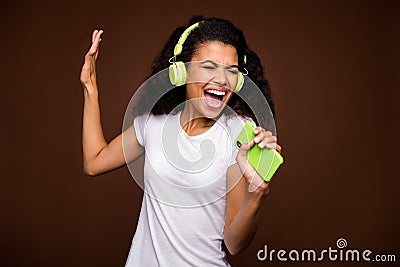 Portrait of funky afro american youth imagine she perform rock concert sing song use smartphone mic listen music on Stock Photo