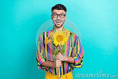 Portrait of funky cheerful man arms hold bunch sunflowers beaming smile isolated on emerald color background Stock Photo