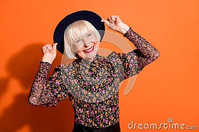 Portrait of funky positive good mood happy old woman wear headwear smiling on camera on orange color background Stock Photo