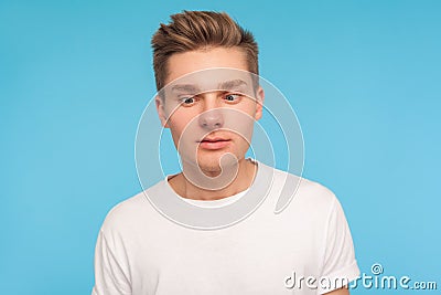 Portrait of funny comic young man in casual white t-shirt looking cross-eyed with awkward silly dumb expression Stock Photo
