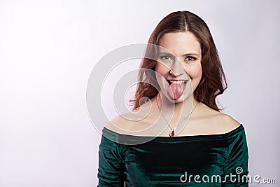 Portrait of funny crazy woman with freckles and classic green dress with tongue. Stock Photo