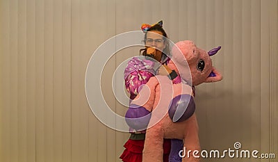 Portrait of a funny and cute transgender girl holding a stuffed pink unicorn and sucking her thumb, Infantile adult behavior, LGBT Stock Photo