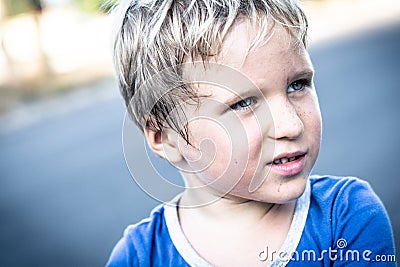 Portrait of a funny happy mischievous cheerful cute blond blue eyed boy making freckles dirty face while playing Stock Photo