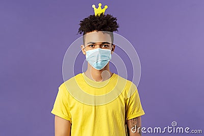 Portrait of funny hispanic guy in face mask, fool around, going crazy staying inside home during quarantine, wearing Stock Photo