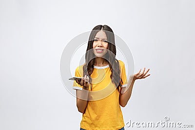 Portrait of a furious asian woman talking on mobile phone over white background Stock Photo