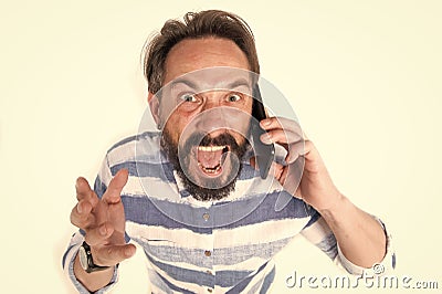 Portrait of furious mature bearded man dressed in shirt with blue lines at mobile phone isolated on white background. Mad Stock Photo