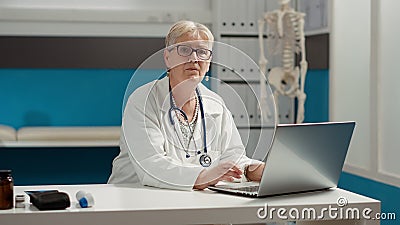 Portrait of general practitioner working on laptop in medical office Stock Photo