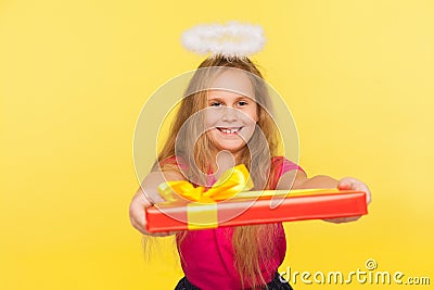 Portrait of generous delighted child girl with long blond hair and angelic halo holding gift box and smiling to camera Stock Photo