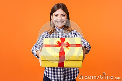 Portrait of generous friendly young woman with brown hair in casual checkered shirt. indoor studio shot isolated on orange Stock Photo