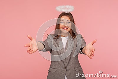 Portrait of generous woman in business suit with angelic appearance and halo over her head raising hands to embrace Stock Photo
