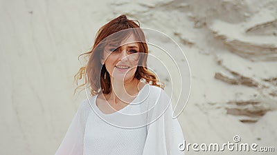 Portrait ginger woman in white dress, looking at camera, stone nature background. Stock Photo